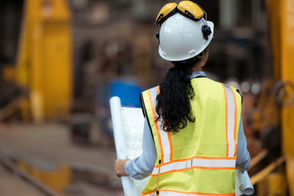 Portrait of railway technician worker in safety vest and helmet working with blueprint at train repair station